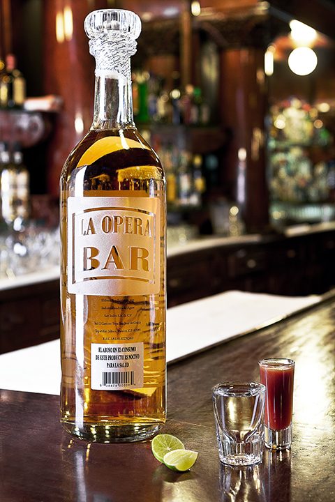 Botella de tequila de la casa junto a un caballito de sangrita
