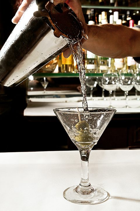 Coctel sirviéndose en una copa de martini en la barra